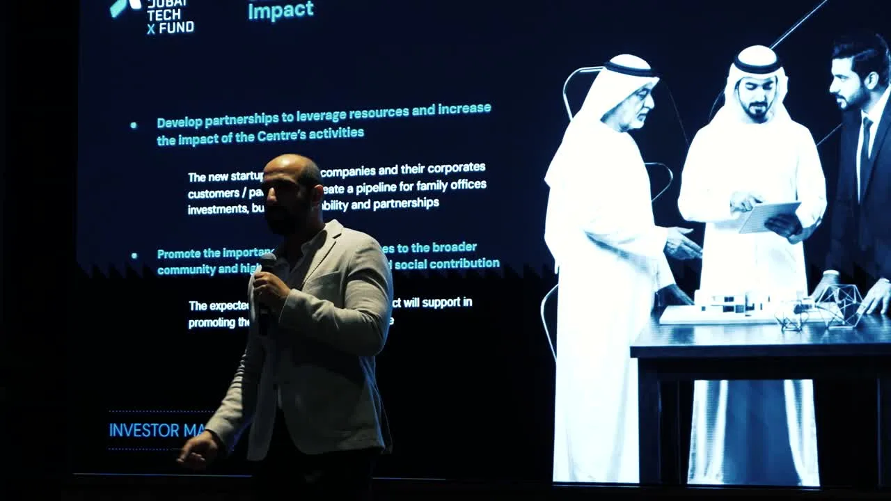 Speaker on stage in front of a Dubai TechX Fund slide at the Investor Majlis